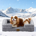 Dog lying on Cozy Kiss grey pet bed in a snowy landscape with mountains.