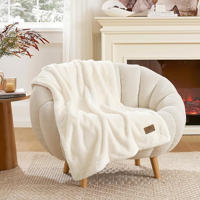 Cozy Kiss leakproof faux fur pet blanket draped over an armchair in a cozy living room setting. #color_Cream White